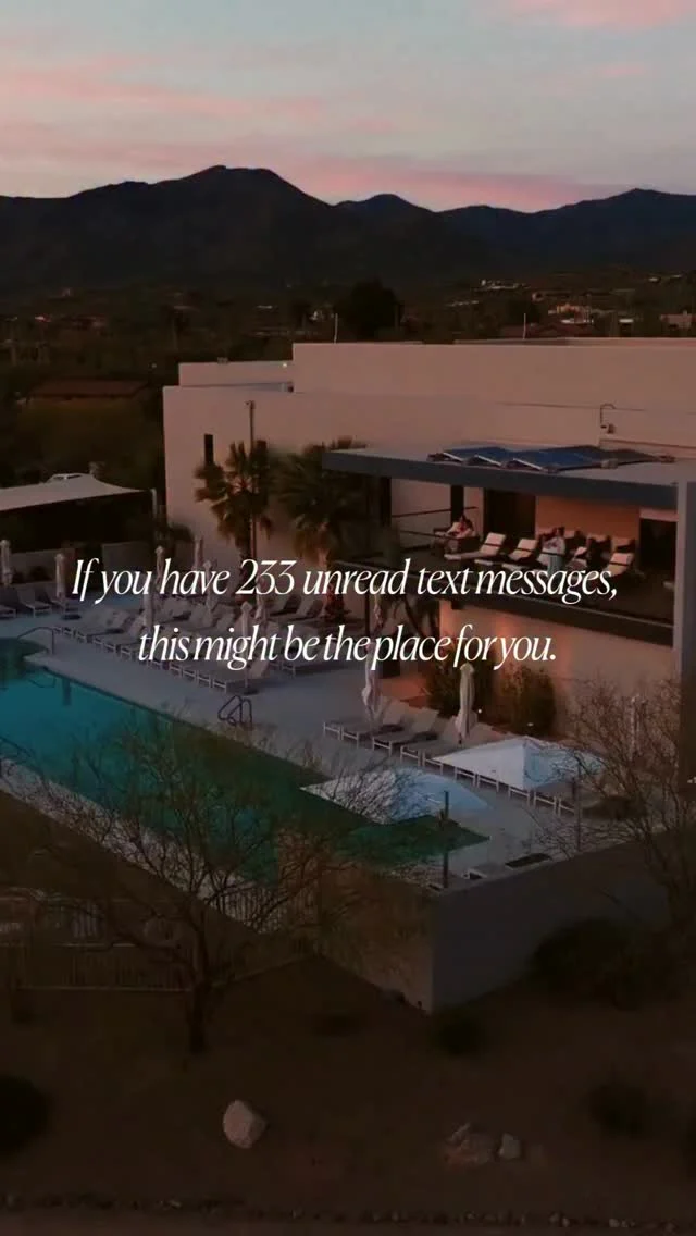 Aerial view of a modern resort with a pool and mountain view at dusk.